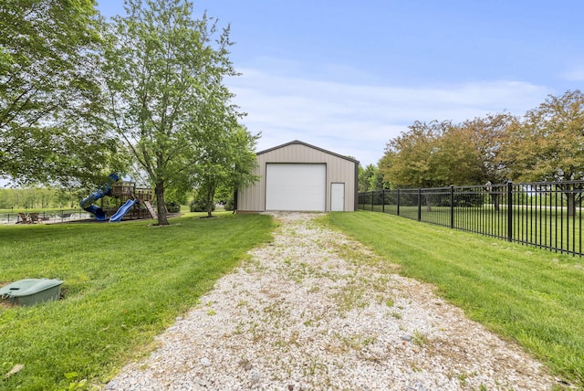 view of yard with a garage, a playground, driveway, and an outdoor structure