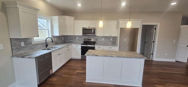 kitchen with appliances with stainless steel finishes, a sink, baseboards, a center island, and light stone countertops