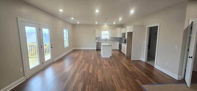 kitchen with stainless steel appliances, a center island, a sink, dark wood finished floors, and white cabinetry