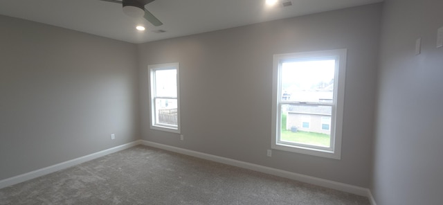 spare room featuring plenty of natural light, ceiling fan, light carpet, and baseboards