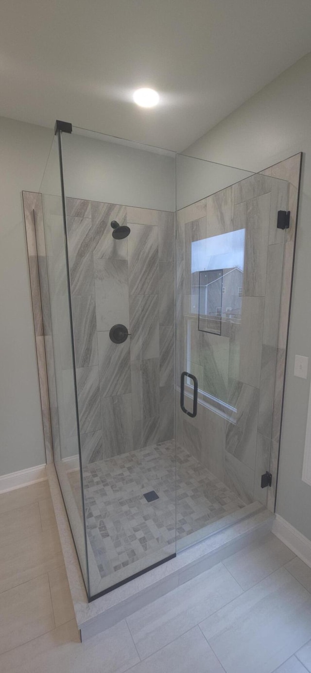 bathroom with tile patterned floors, a stall shower, and baseboards