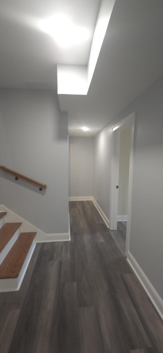 below grade area with baseboards, wood finished floors, and stairway