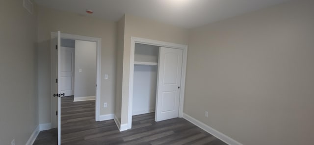 unfurnished bedroom with dark wood-style flooring, baseboards, and a closet