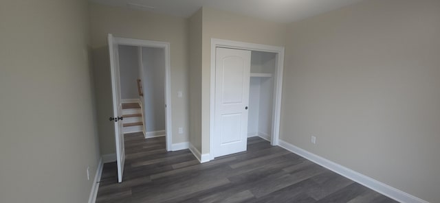 unfurnished bedroom with dark wood-style floors, a closet, and baseboards