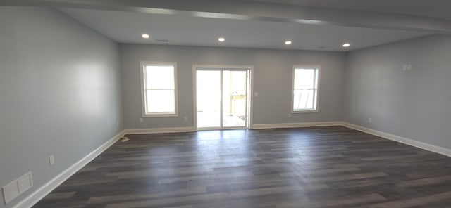 empty room with plenty of natural light, baseboards, recessed lighting, and dark wood finished floors