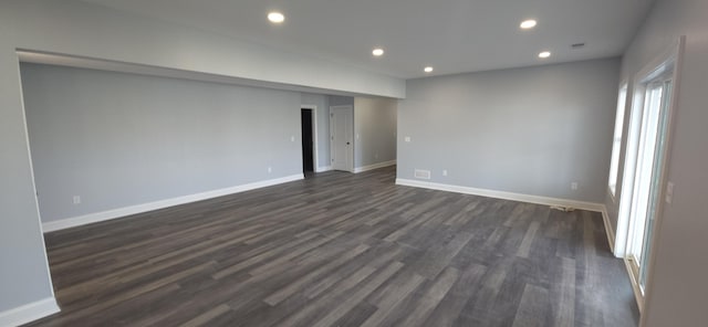 spare room featuring recessed lighting, dark wood-style flooring, and baseboards