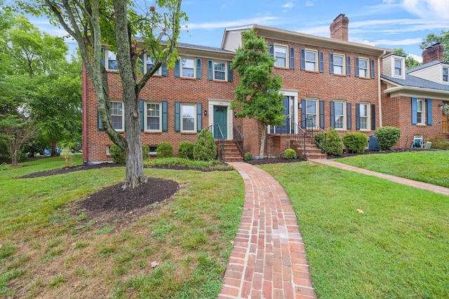 multi unit property featuring brick siding, a front yard, and a chimney