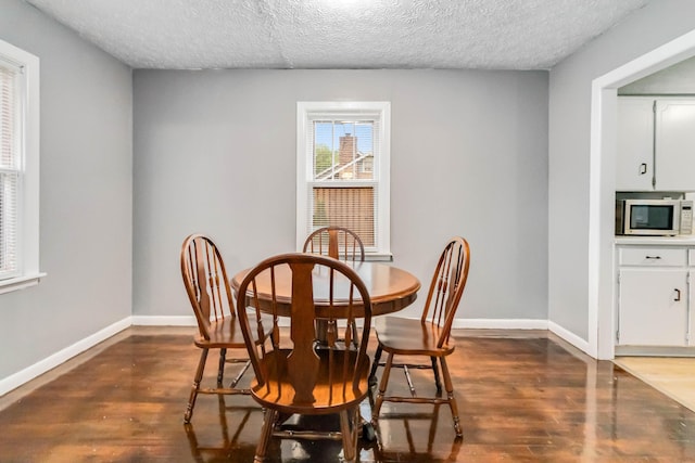 dining room featuring a textured ceiling, dark wood-style flooring, and baseboards