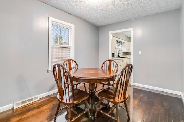 dining space with dark wood finished floors, baseboards, and a textured ceiling