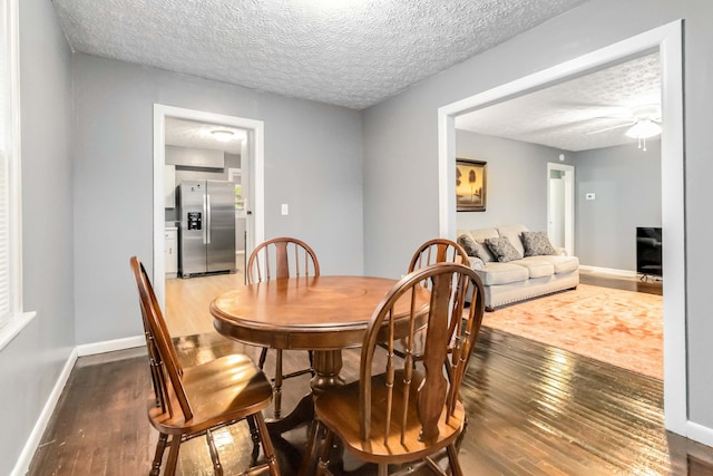dining area featuring wood finished floors, a textured ceiling, baseboards, and a ceiling fan