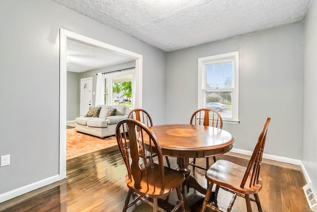 dining space featuring dark wood-type flooring, baseboards, and a textured ceiling