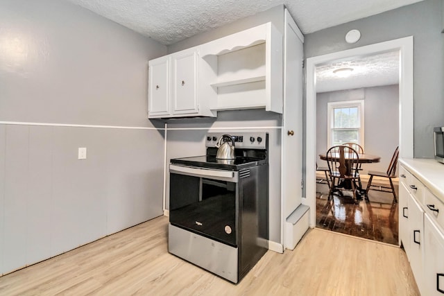 kitchen featuring electric stove, light wood-type flooring, open shelves, white cabinets, and a textured ceiling