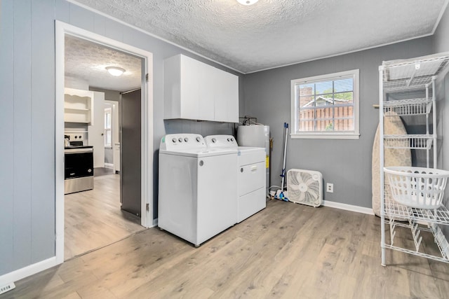 washroom featuring a textured ceiling, light wood-style floors, washing machine and clothes dryer, baseboards, and cabinet space