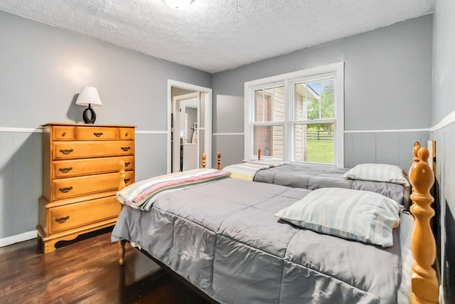 bedroom featuring dark wood finished floors, a textured ceiling, and baseboards