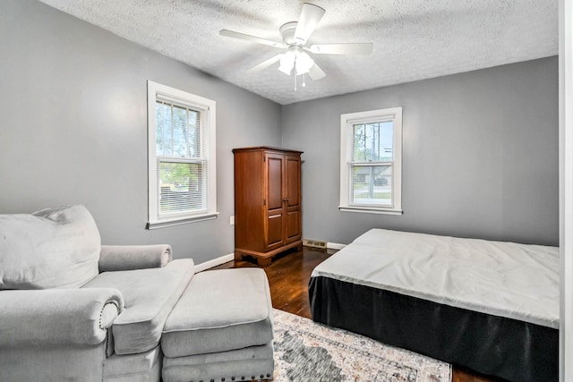 bedroom with a textured ceiling, dark wood finished floors, baseboards, and a ceiling fan