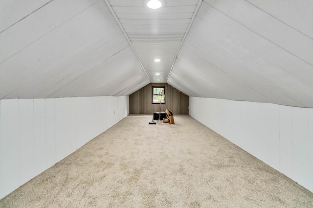 additional living space with lofted ceiling, carpet flooring, and wood walls