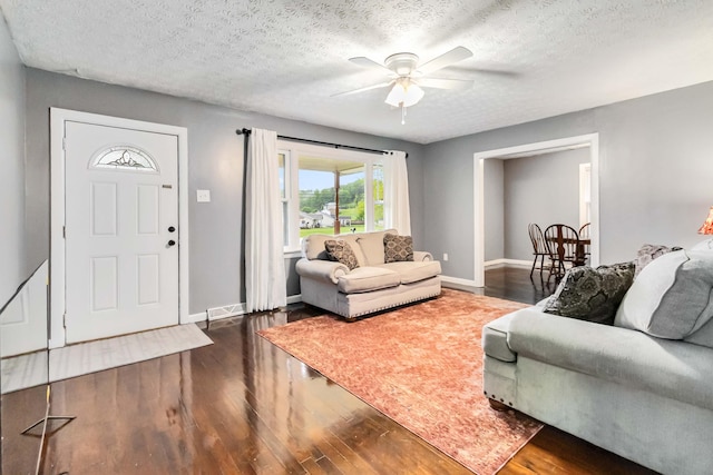 living area featuring a ceiling fan, baseboards, wood finished floors, and a textured ceiling
