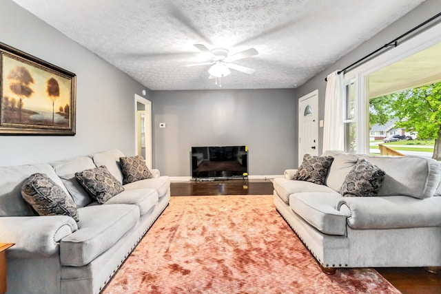 living area featuring wood finished floors, a ceiling fan, a textured ceiling, and baseboards