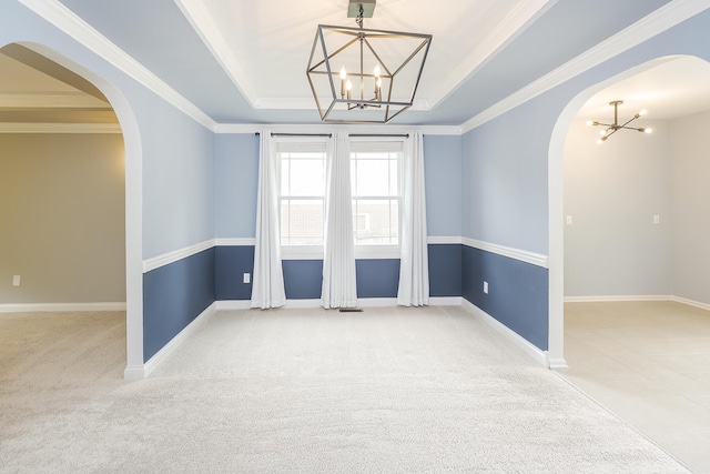 spare room with a chandelier, a tray ceiling, arched walkways, carpet floors, and crown molding