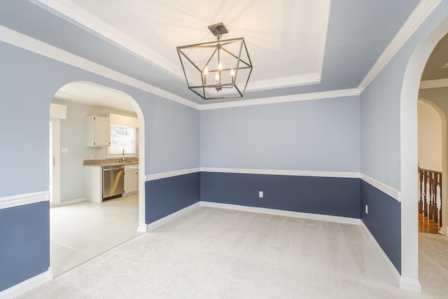 unfurnished room with a tray ceiling, a chandelier, arched walkways, a sink, and ornamental molding