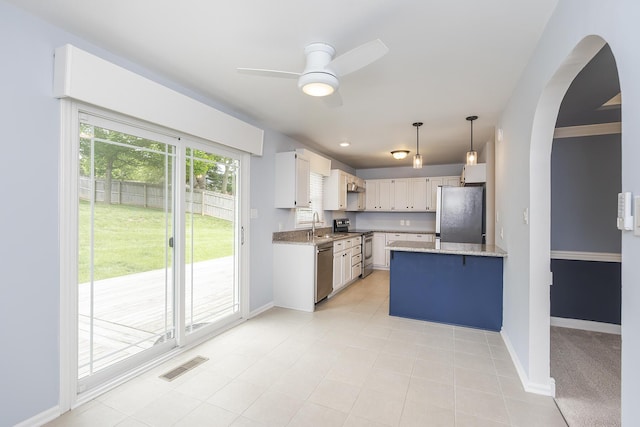 kitchen featuring stainless steel appliances, a peninsula, baseboards, light stone countertops, and arched walkways