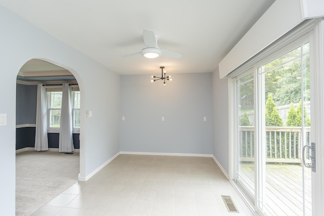 spare room with arched walkways, healthy amount of natural light, a chandelier, and baseboards