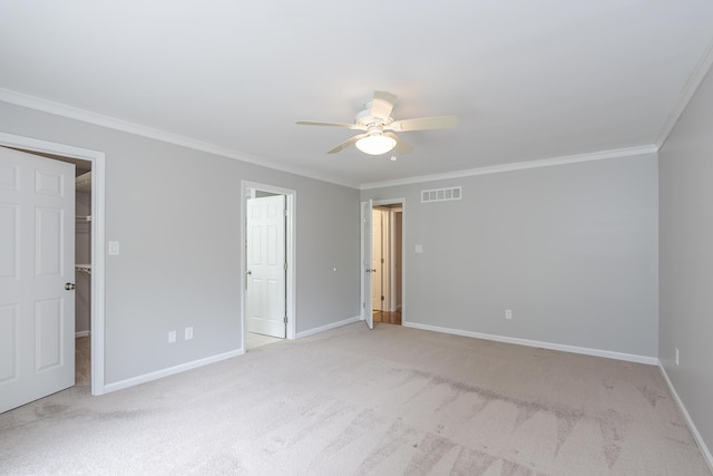 unfurnished bedroom with crown molding, light carpet, baseboards, a spacious closet, and a ceiling fan