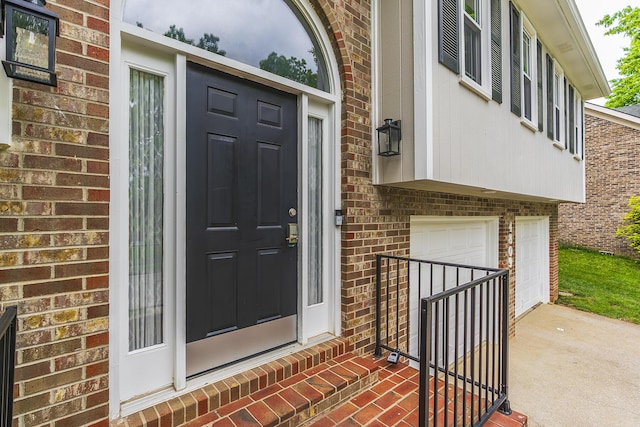 doorway to property with brick siding, driveway, and an attached garage