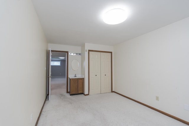 unfurnished bedroom with light carpet, a closet, and baseboards