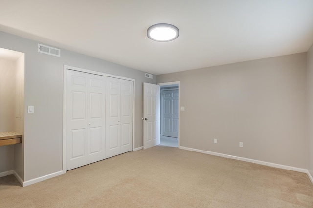 unfurnished bedroom with light carpet, baseboards, and a closet