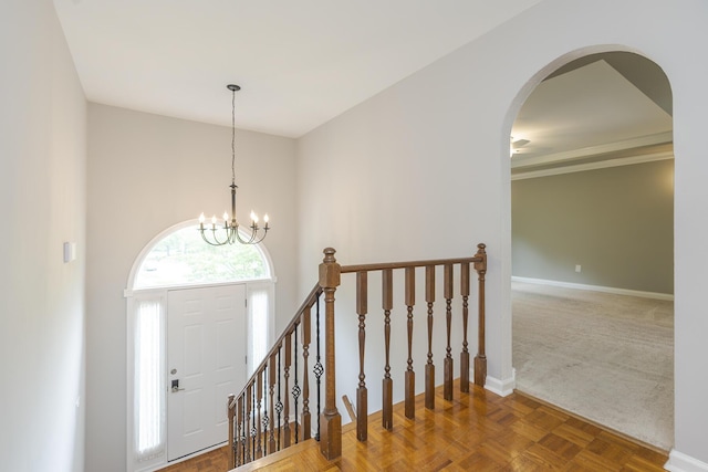 foyer featuring baseboards, arched walkways, and a chandelier