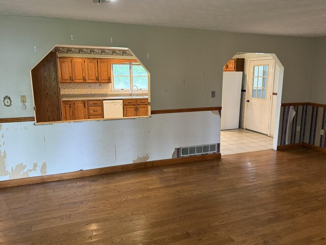 8023 Old Richmond Rd, Lexington, KY 40515 - kitchen featuring white dishwasher, arched walkways, light wood finished floors, a sink, and brown cabinets