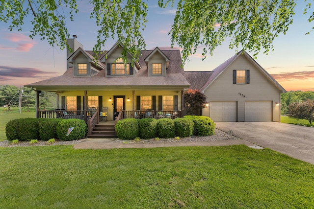 view of front of home featuring a chimney, concrete driveway, a porch, a front lawn, and a garage