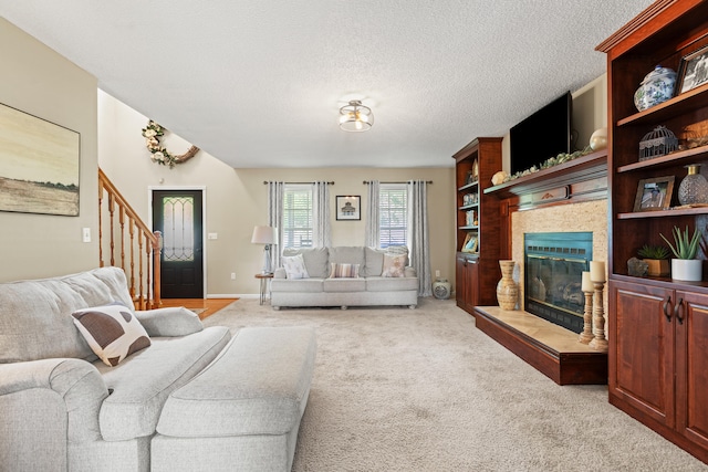 living room with stairway, light colored carpet, a tiled fireplace, a textured ceiling, and baseboards