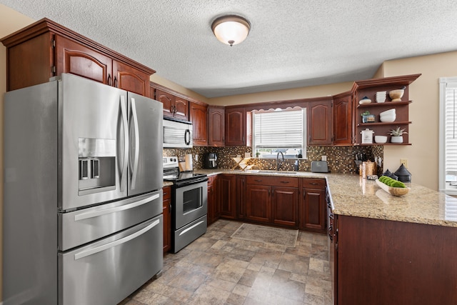 kitchen with appliances with stainless steel finishes, a sink, backsplash, a textured ceiling, and open shelves