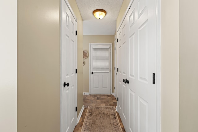 entryway featuring baseboards, a textured ceiling, and dark stone finish floors