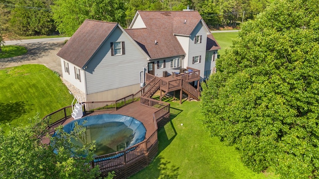 view of pool featuring a wooden deck, a lawn, and stairs