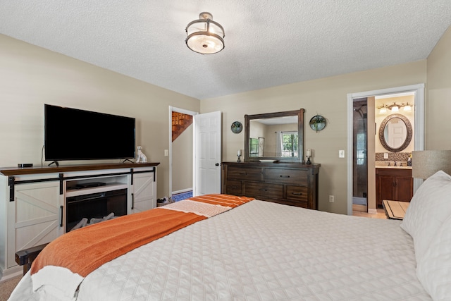 bedroom with a sink, a textured ceiling, and connected bathroom