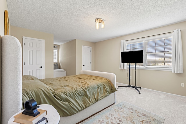 bedroom with baseboards, carpet floors, and a textured ceiling