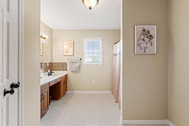 full bath featuring backsplash, vanity, a textured ceiling, and baseboards