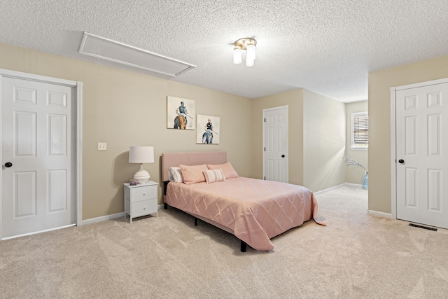carpeted bedroom featuring attic access, a textured ceiling, and baseboards