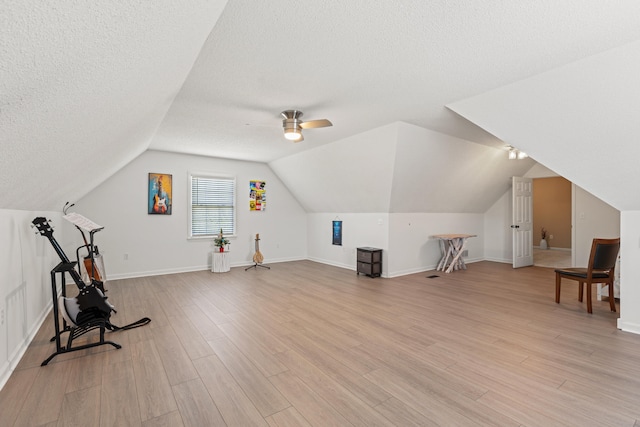 bonus room featuring a textured ceiling, light wood-style flooring, a ceiling fan, vaulted ceiling, and baseboards