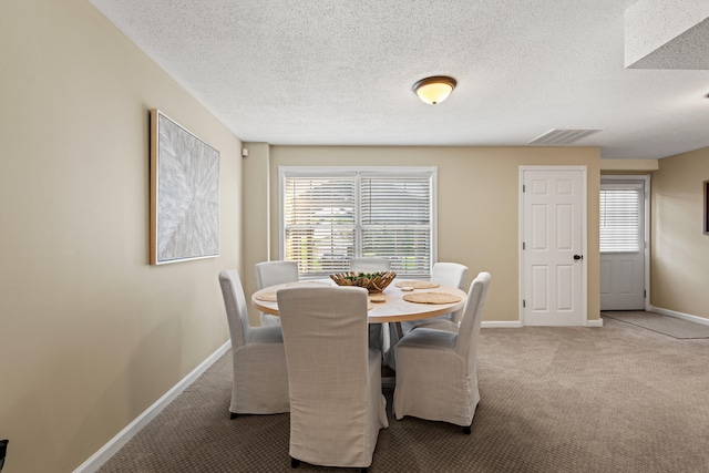 carpeted dining area with baseboards, healthy amount of natural light, and a textured ceiling