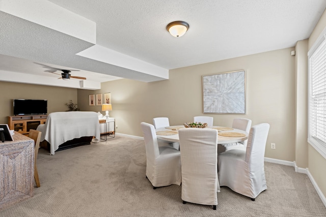 dining space featuring ceiling fan, light carpet, baseboards, and a textured ceiling