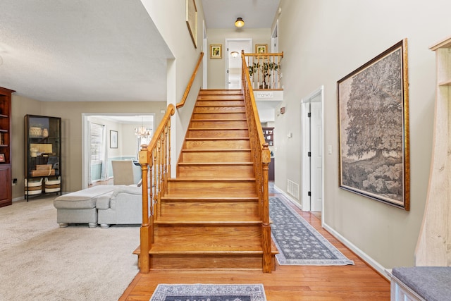staircase featuring a chandelier, baseboards, and wood finished floors