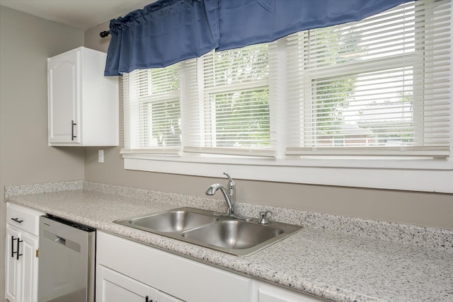 kitchen featuring stainless steel dishwasher, a sink, white cabinets, and light countertops