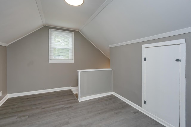 additional living space with vaulted ceiling, wood finished floors, and baseboards