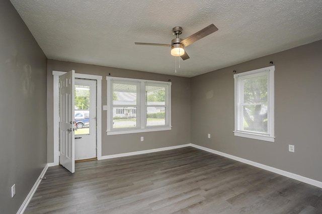 empty room featuring ceiling fan, dark wood-style flooring, a textured ceiling, and baseboards