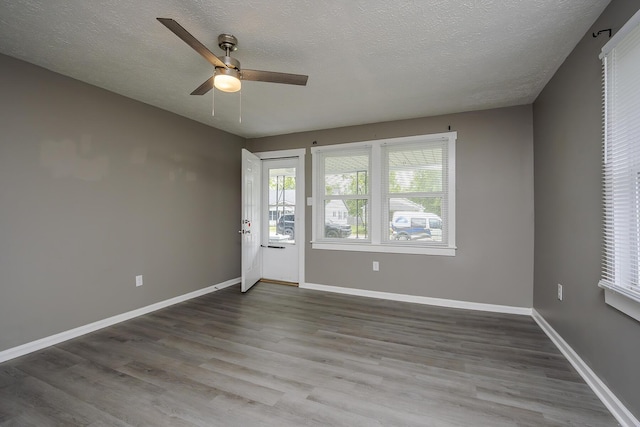 empty room featuring ceiling fan, wood finished floors, baseboards, and a textured ceiling