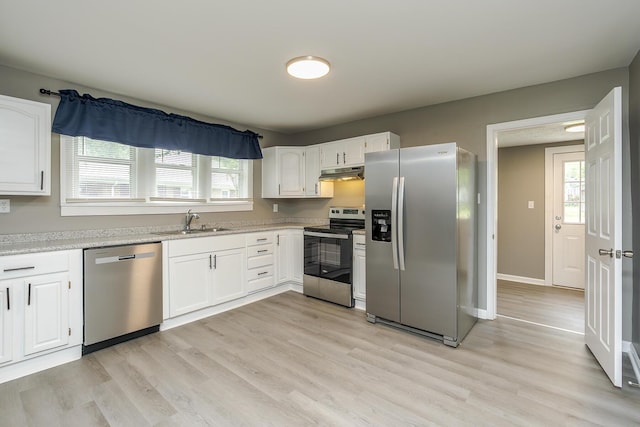 kitchen featuring stainless steel appliances, under cabinet range hood, a sink, and white cabinets